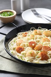 Delicious scallop pasta with green onion served on grey table, closeup