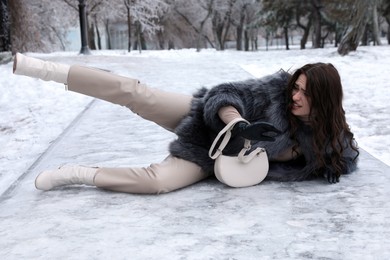 Young woman fallen on slippery icy pavement in park