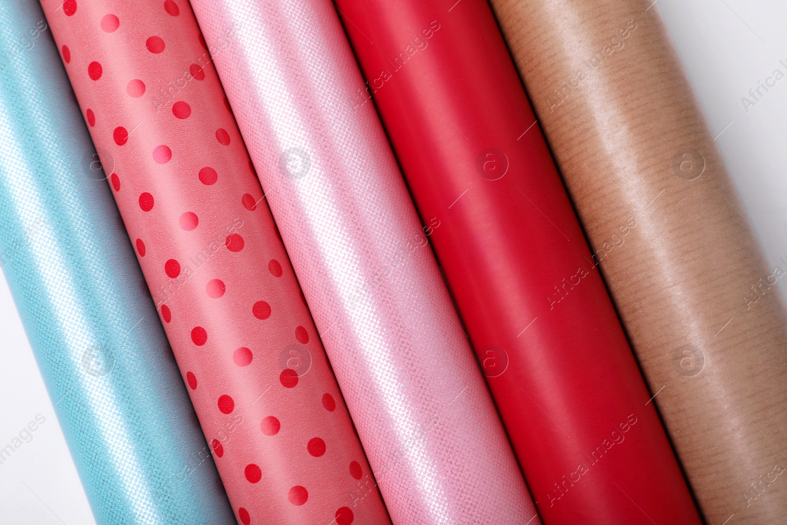 Photo of Rolls of different bright wrapping paper on white background, top view