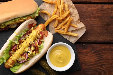 Delicious hot dogs with lettuce, onion and pickle served on wooden table, flat lay. Space for text