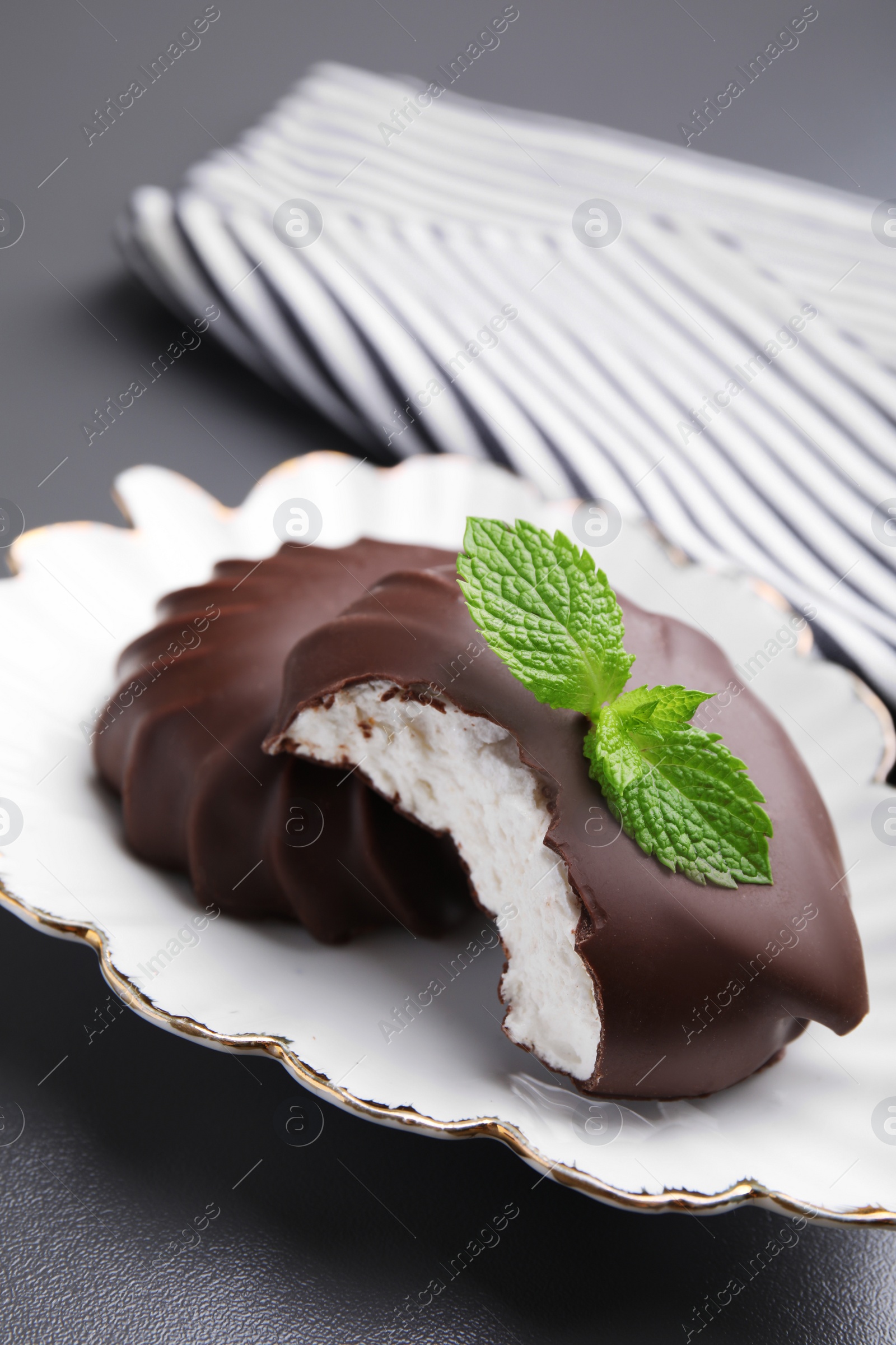 Photo of Delicious chocolate covered zephyrs with mint on black table, closeup