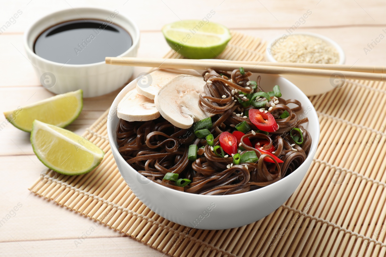 Photo of Tasty buckwheat noodles (soba) with mushrooms, onion and chili pepper served on wooden table