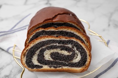 Photo of Slices of poppy seed roll on white marble table, closeup. Tasty cake