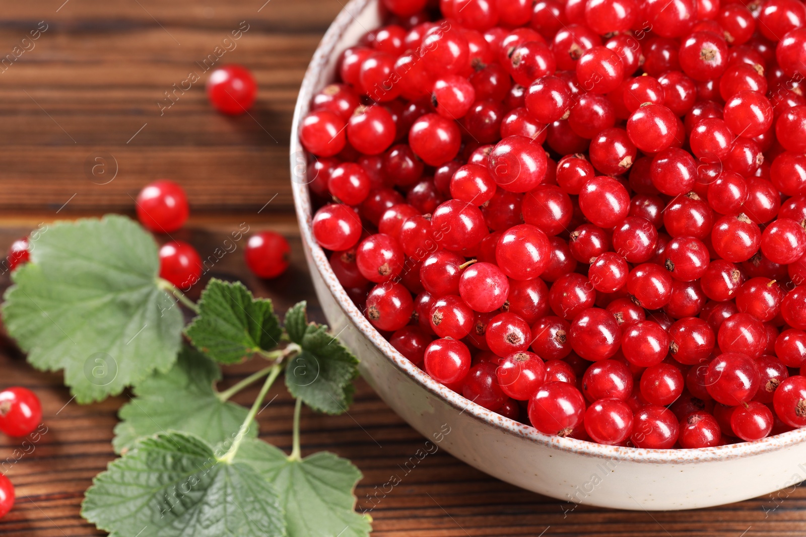 Photo of Ripe red currants and leaves on wooden table, closeup