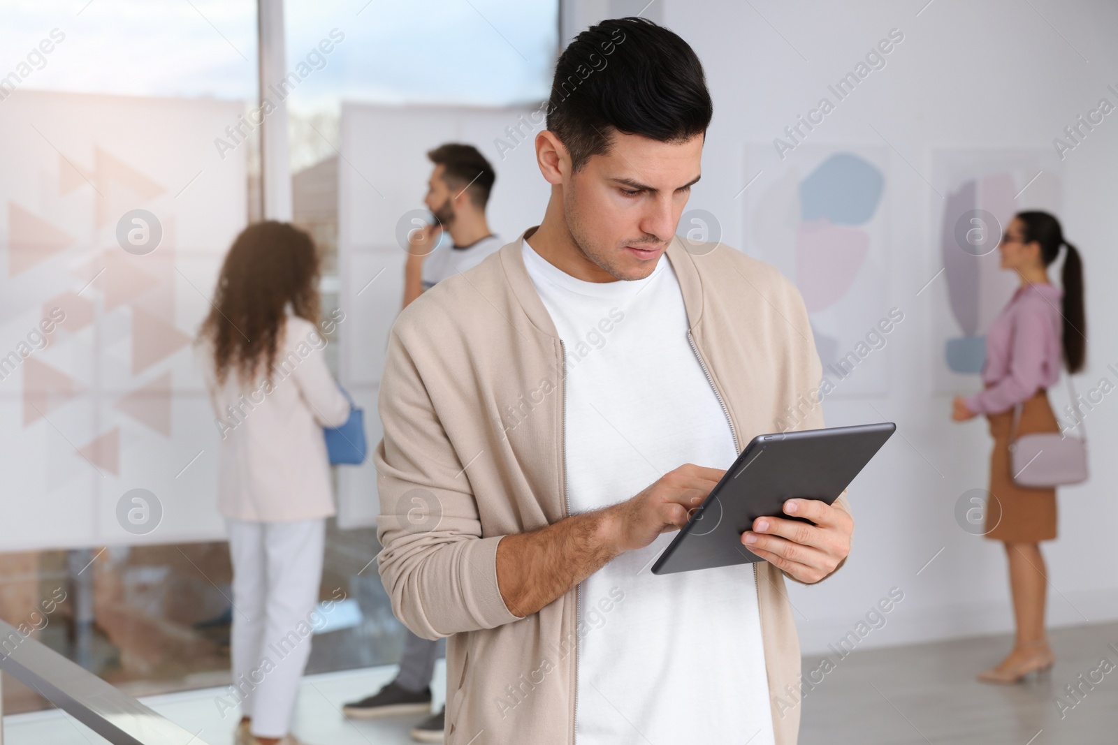 Photo of Thoughtful man with tablet at exhibition in art gallery