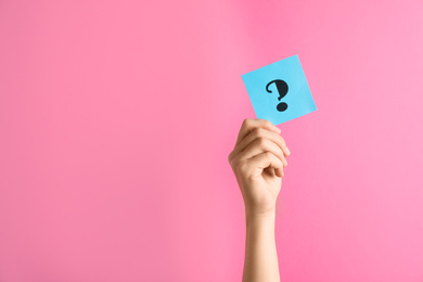 Photo of Woman holding note with question mark on pink background, closeup. Space for text