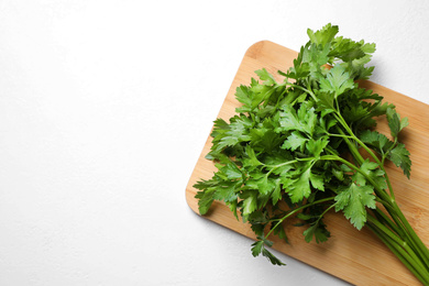 Photo of Wooden board with fresh green parsley on white table, top view. Space for text