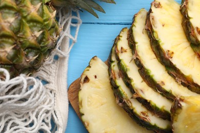 Photo of Slices of ripe pineapple on light blue wooden table, flat lay