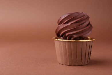 Photo of Delicious chocolate cupcake on brown background, closeup. Space for text