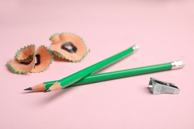 Pencils, sharpener and shavings on pink background