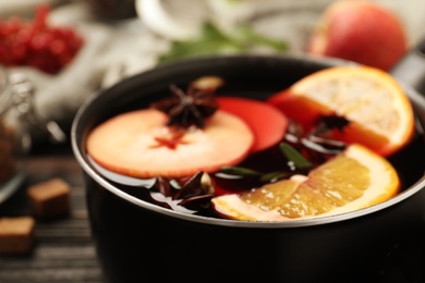 Photo of Saucepan with tasty mulled wine on black wooden table, closeup