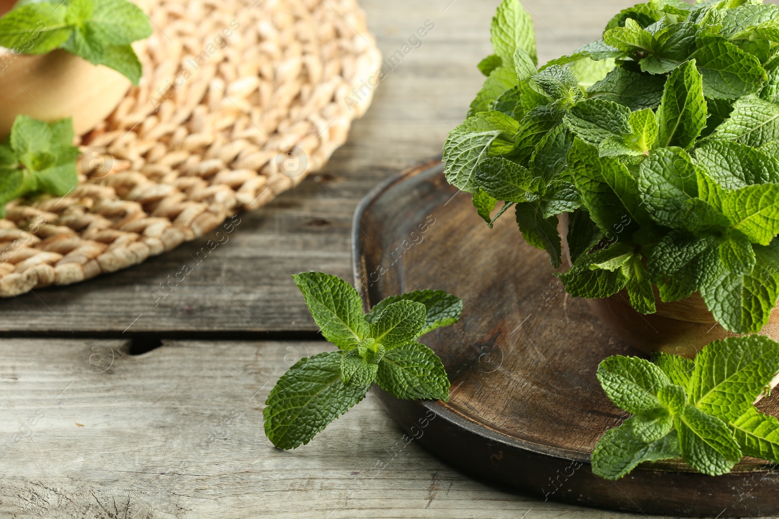 Photo of Bowl with fresh green mint leaves on wooden table, closeup. Space for text