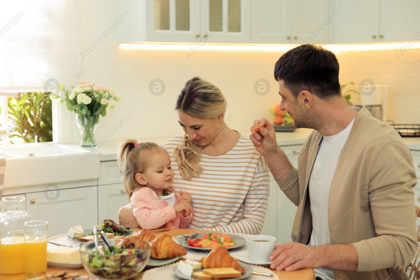 Photo of Happy family having breakfast together at table in kitchen