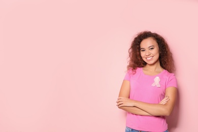 Photo of African-American woman with silk ribbon and space for text on color background. Breast cancer awareness concept