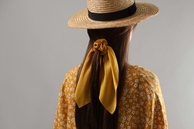 Photo of Woman with hat and stylish yellow bandana on light grey background, back view
