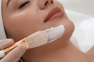 Photo of Young woman during face peeling procedure in salon, closeup