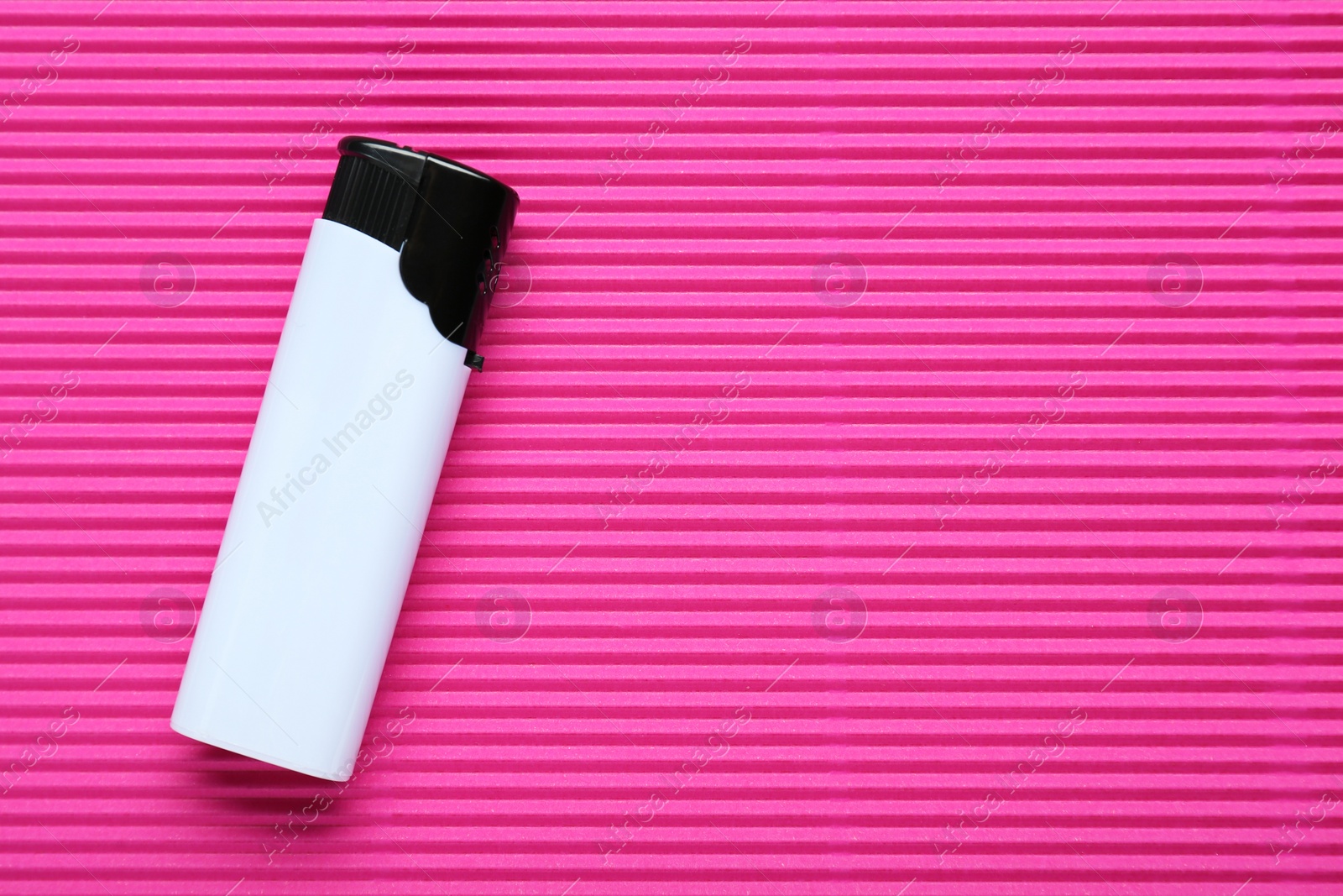 Photo of Stylish small pocket lighter on pink corrugated fiberboard, top view. Space for text