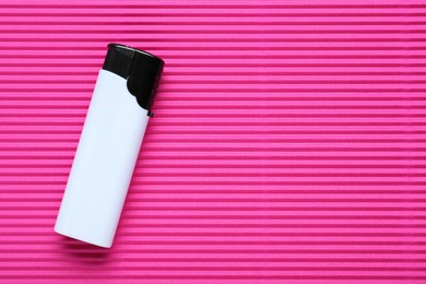 Photo of Stylish small pocket lighter on pink corrugated fiberboard, top view. Space for text