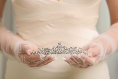 Photo of Bride holding luxurious tiara on grey background, closeup view