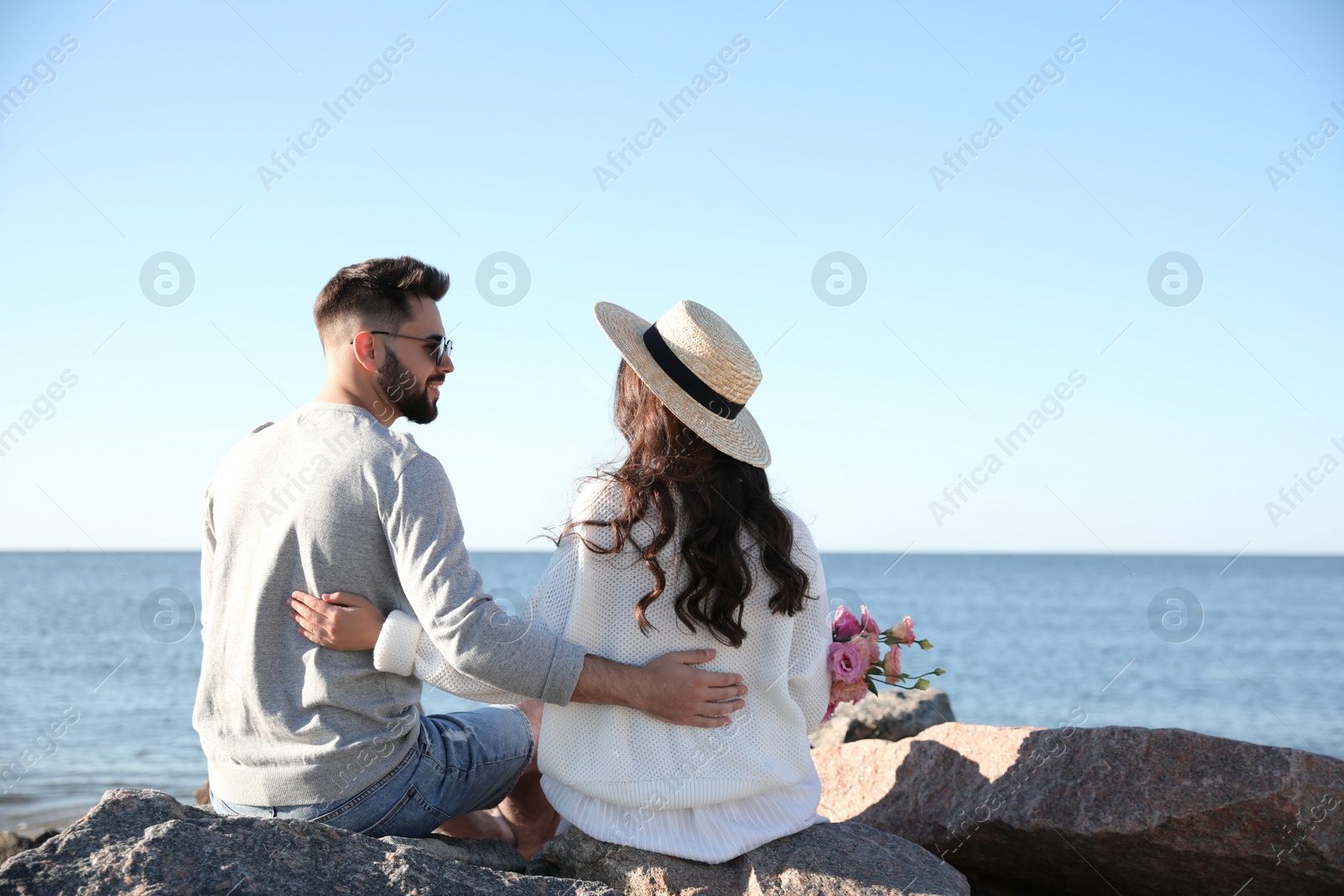 Photo of Happy young couple with flowers on beach. Honeymoon trip