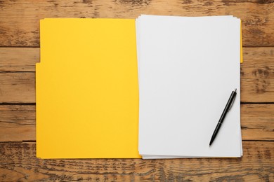 Photo of Yellow file with blank sheets of paper and pen on wooden table, top view. Space for design