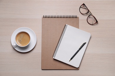 Photo of Notebooks, coffee and glasses on wooden table, flat lay