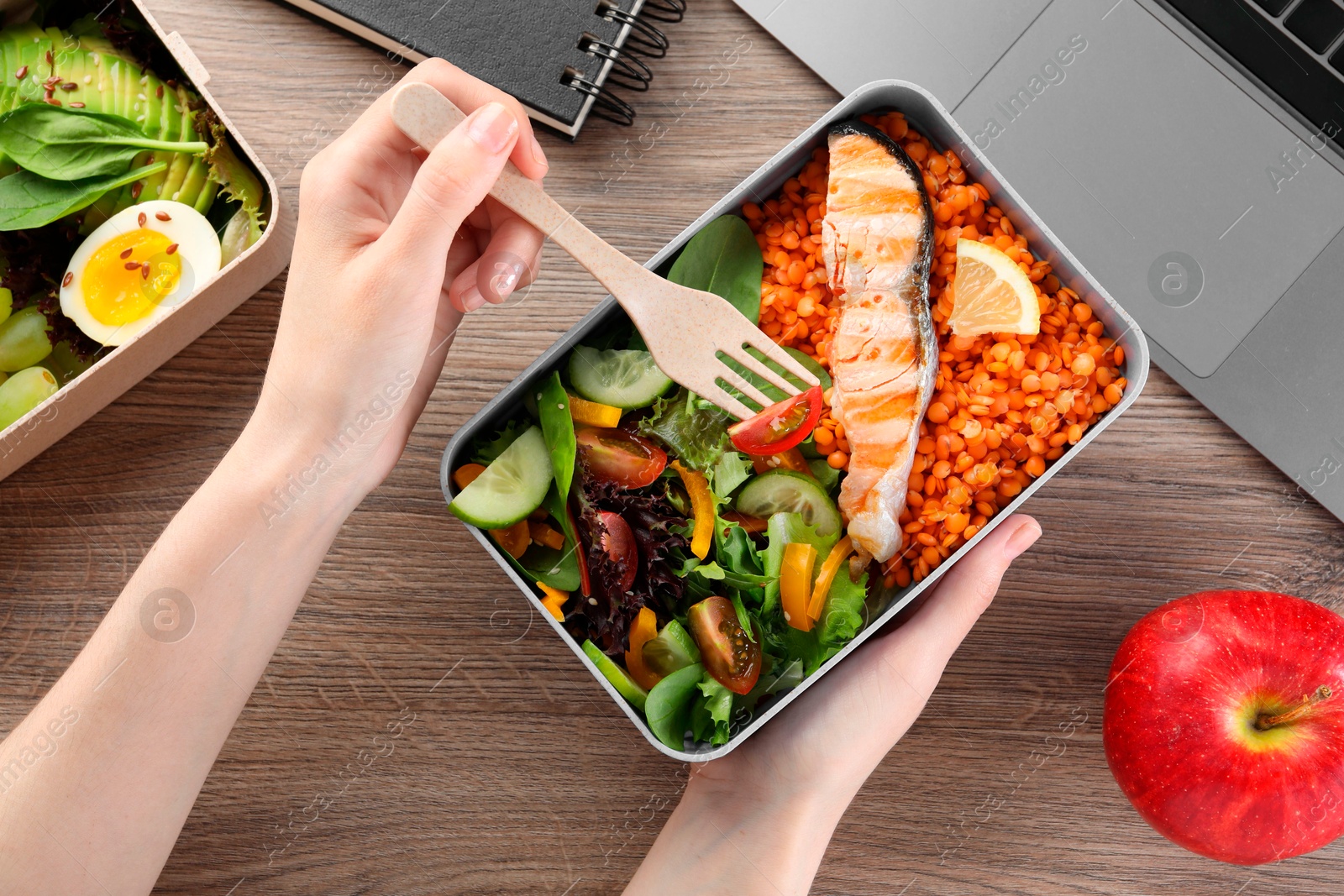 Photo of Woman eating healthy products high in vegetable fats near laptop at wooden table, top view