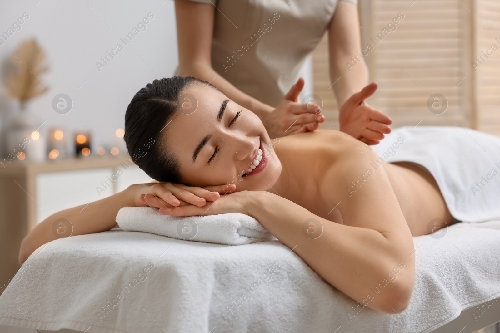 Photo of Woman receiving back massage on couch in spa salon