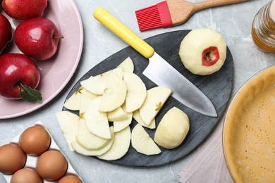 Photo of Cut fresh apple with knife and board on grey table, flat lay. Baking pie