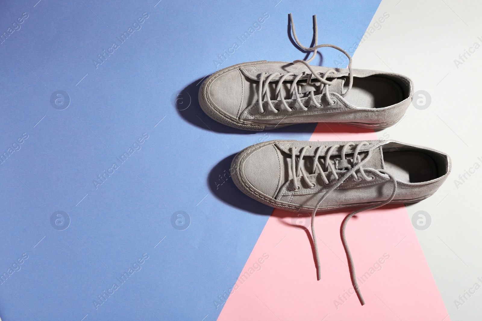 Photo of Pair of stylish sneakers on color background, top view with space for text