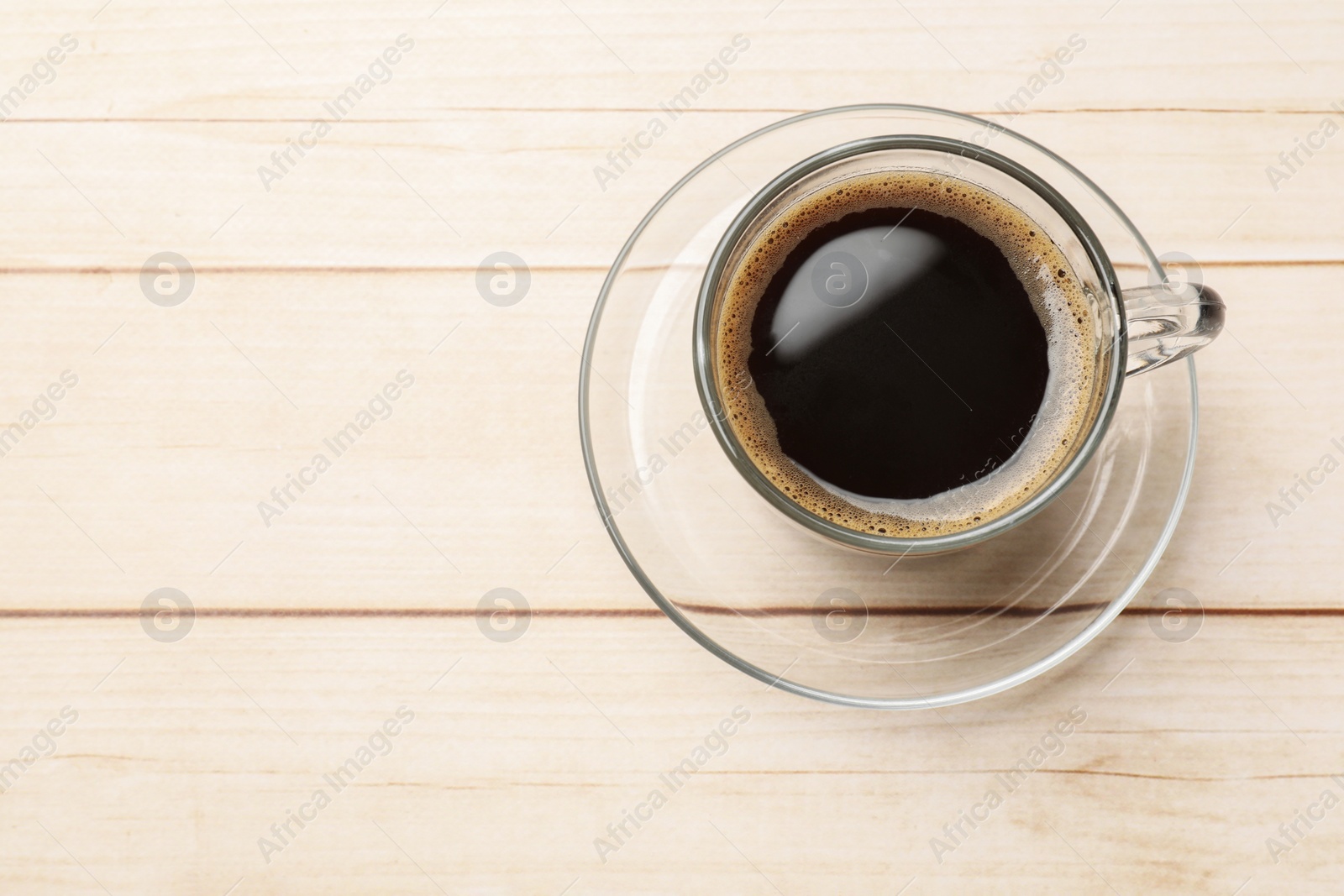 Photo of Cup of aromatic coffee on light wooden table, top view. Space for text