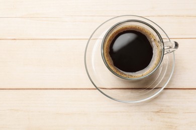 Cup of aromatic coffee on light wooden table, top view. Space for text