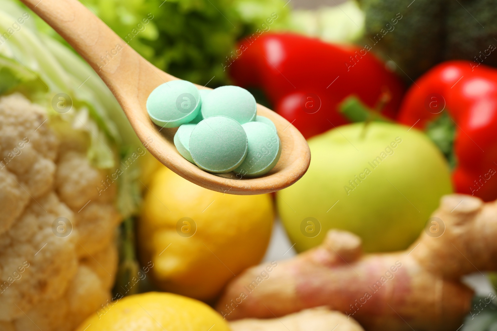 Photo of Dietary supplements in wooden spoon near products, closeup. Space for text