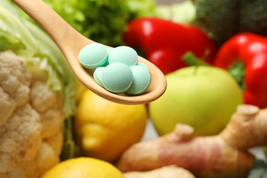 Photo of Dietary supplements in wooden spoon near products, closeup. Space for text