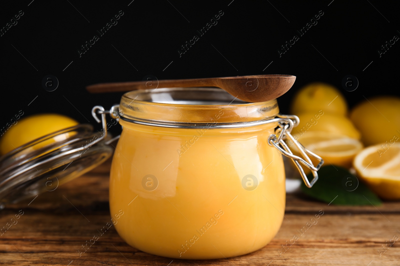 Photo of Delicious lemon curd in glass jar on wooden table