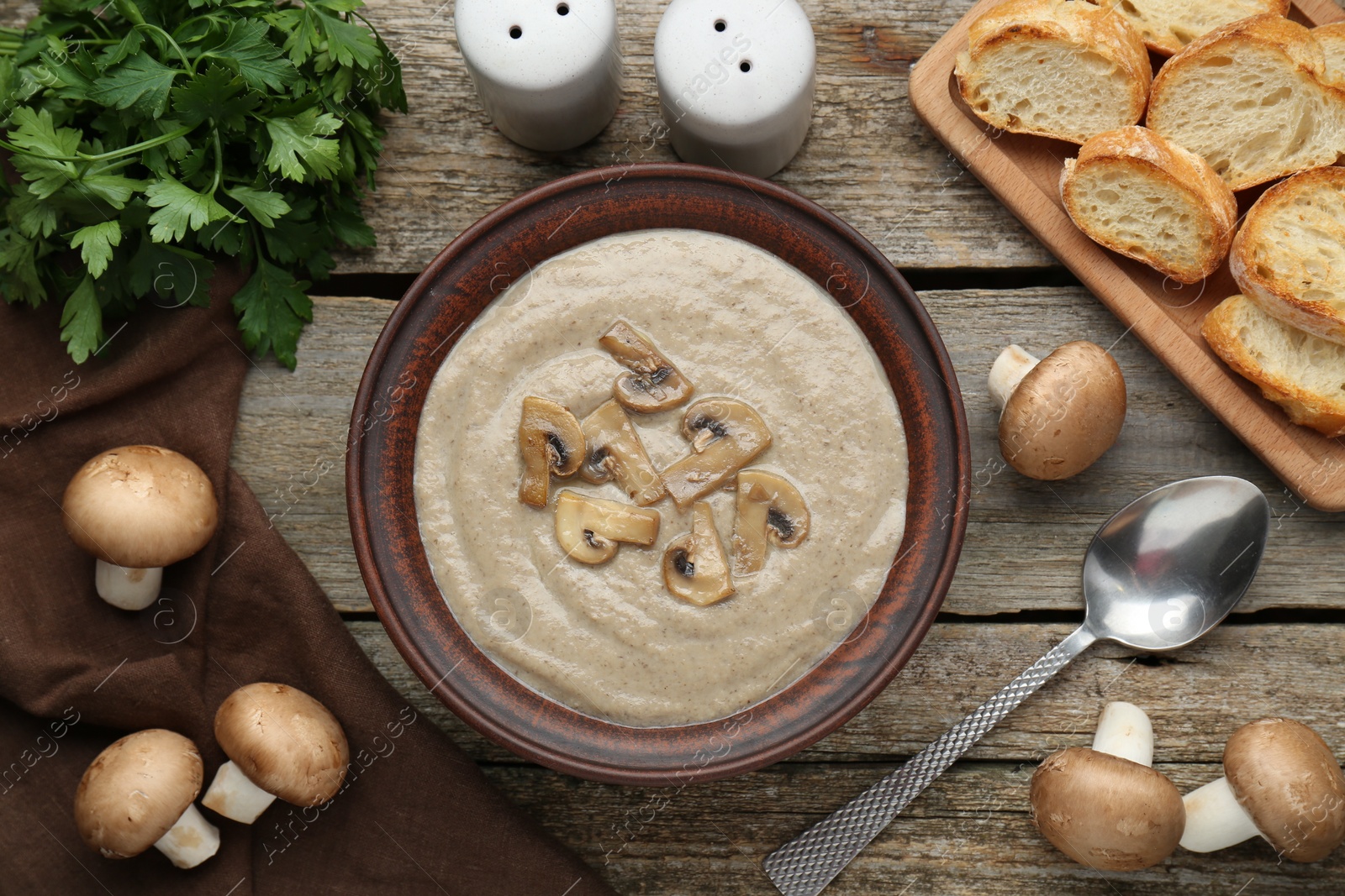 Photo of Delicious mushroom cream soup served on wooden table, flat lay