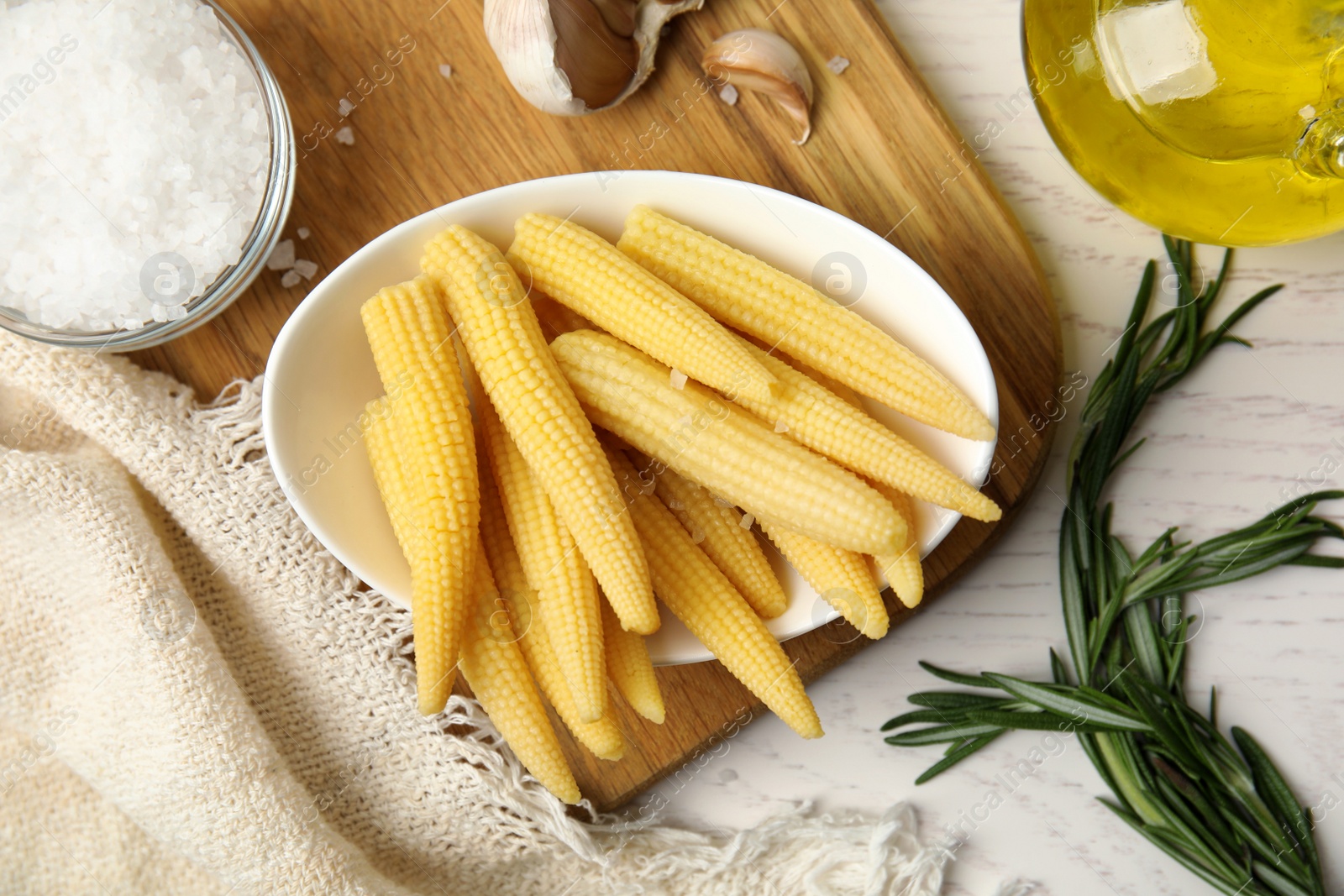 Photo of Fresh baby corn cobs and spices on white wooden table, flat lay