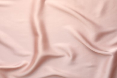 Crumpled pink silk fabric as background, top view