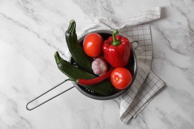 Photo of Fresh vegetables for ratatouille in colander on white marble table, flat lay