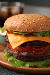 Photo of Tasty cheeseburger with patties and tomato on grey textured table, closeup