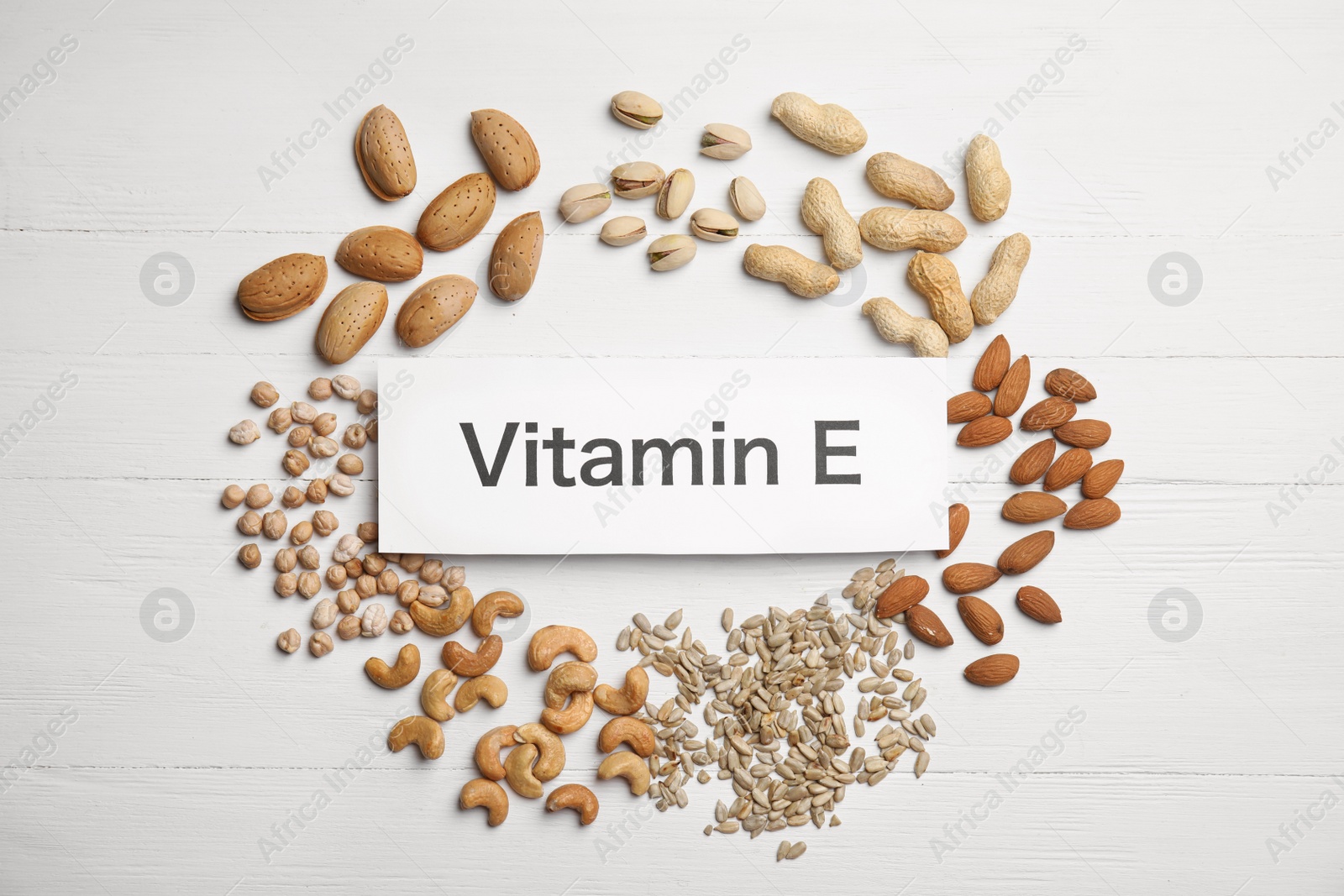 Photo of Card with phrase Vitamin E and different products on white wooden table, flat lay