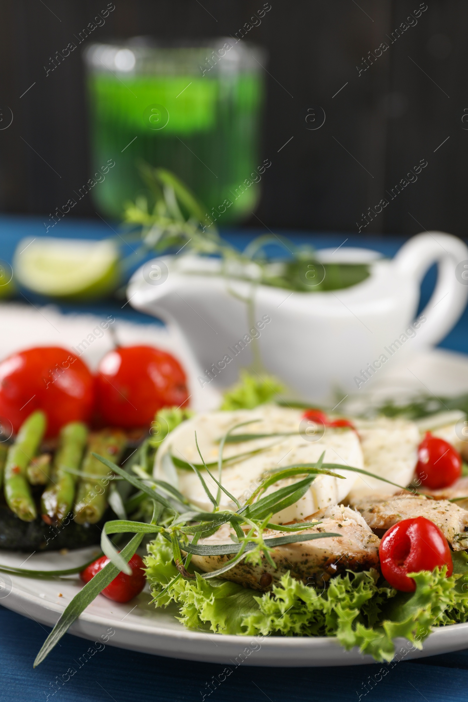 Photo of Tasty mozzarella, chicken and vegetables with tarragon on table, closeup