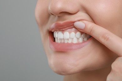 Photo of Woman showing healthy gums on grey background, closeup. Space for text