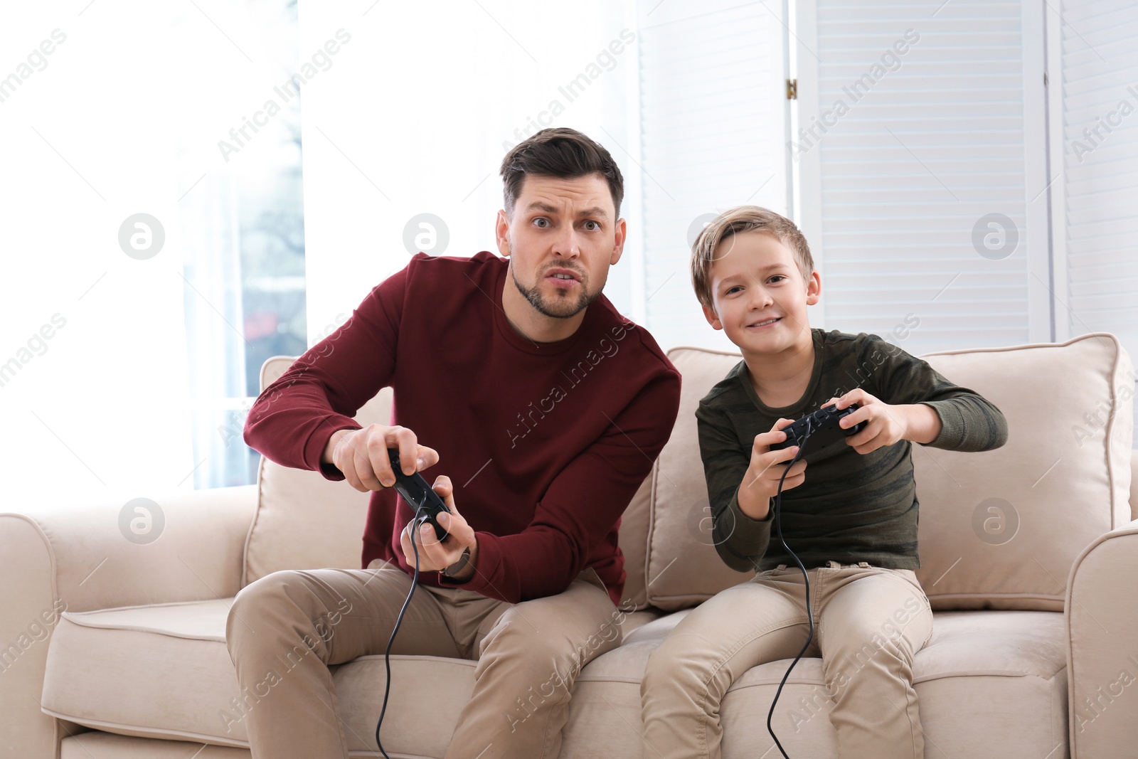 Photo of Father and son playing video games at home