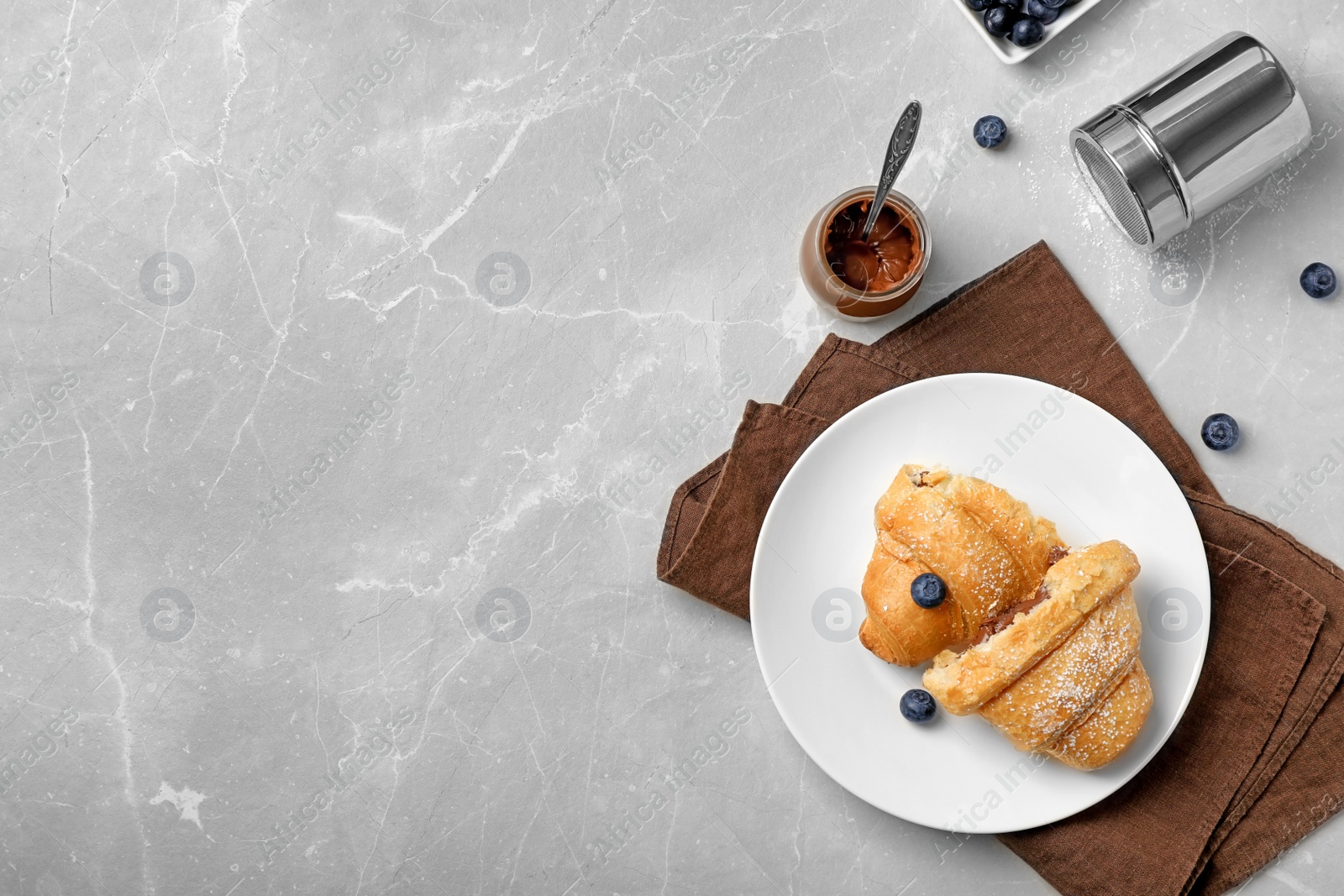 Photo of Tasty croissant with chocolate sauce served for breakfast on table, top view