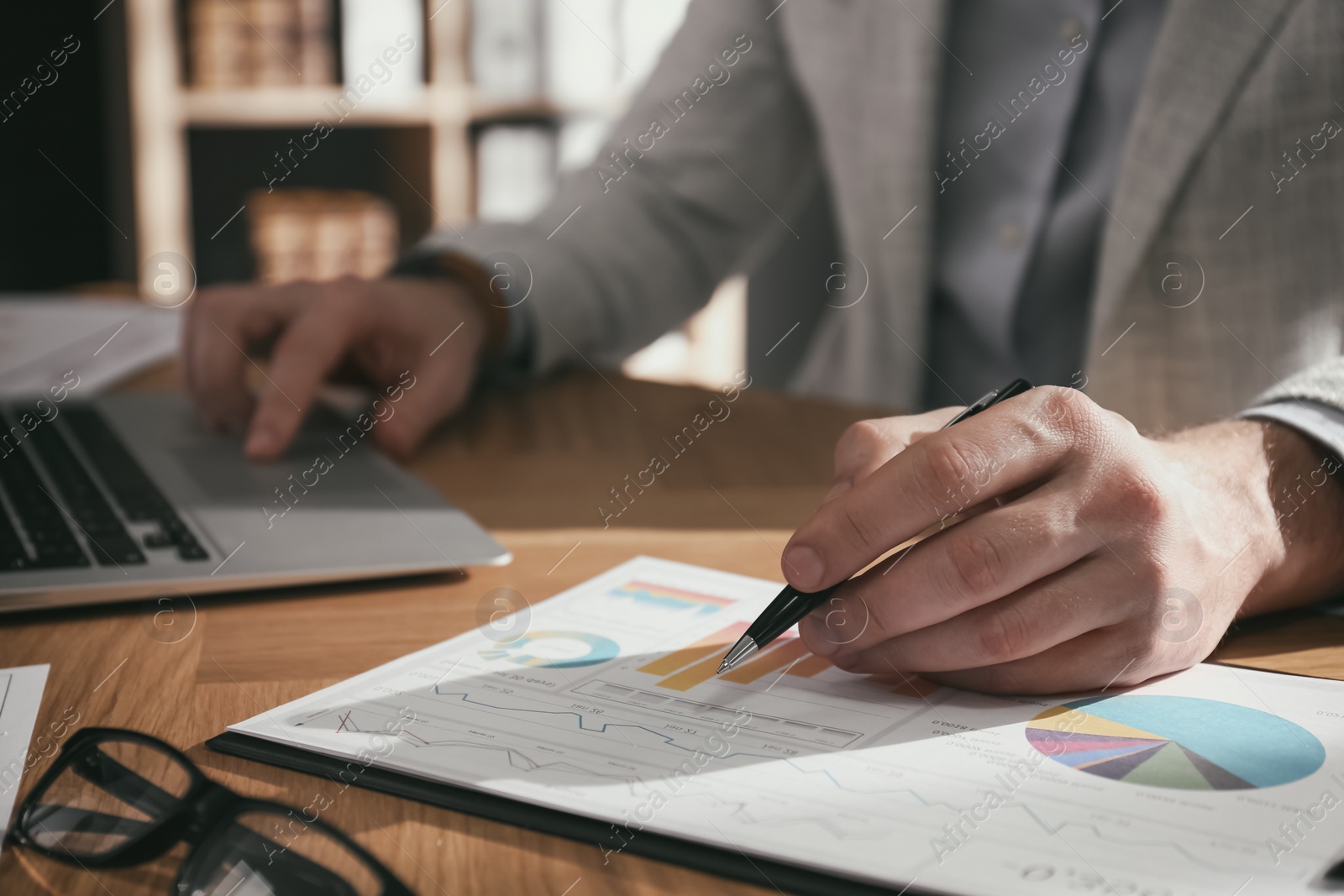 Photo of Businessman working with charts and graphs at table in office, closeup. Investment analysis