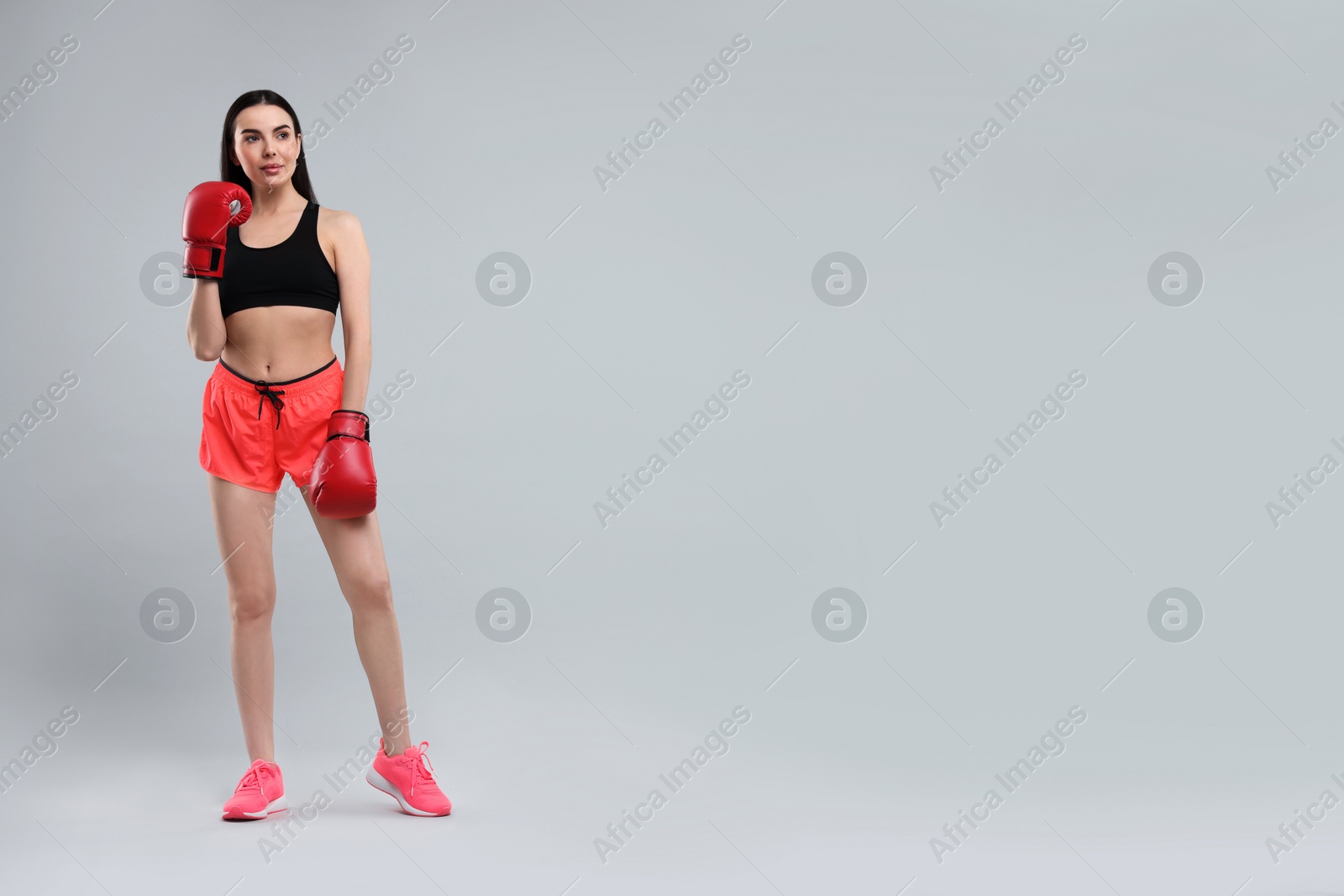 Photo of Beautiful woman in boxing gloves on grey background. Space for text