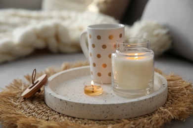 Photo of Cup of drink and burning candles on sofa in room. Interior elements