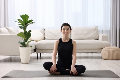 Beautiful girl meditating on yoga mat at home