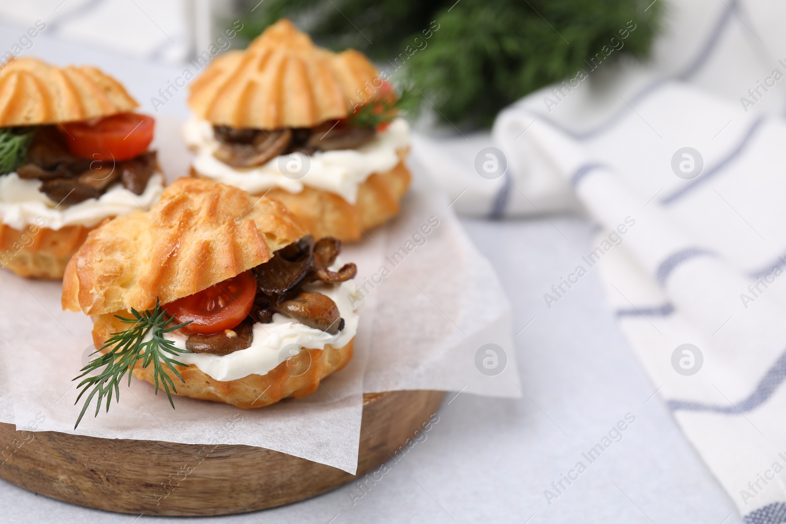 Photo of Delicious profiteroles with cream cheese, mushrooms, tomato and dill on white table, closeup. Space for text